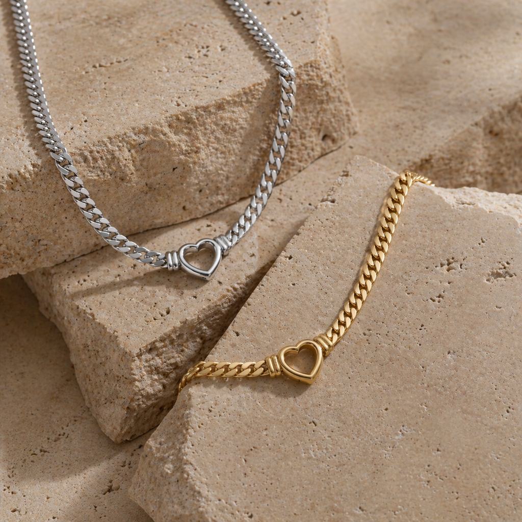 Chunky curb chain necklace with open heart pendant in gold and silver stainless steel on neutral background