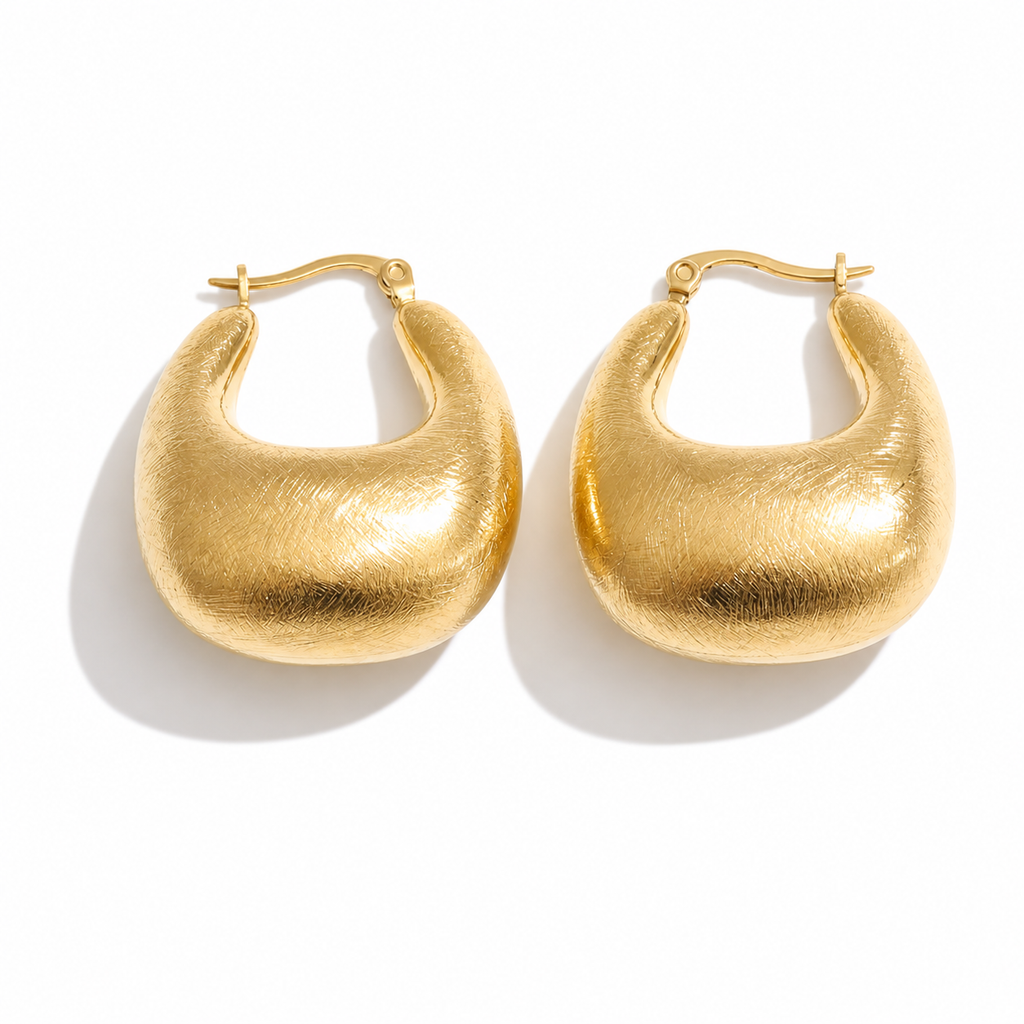 Gold and silver dome hoop earrings with a brushed texture and rounded sculptural shape, shown on a white background.
