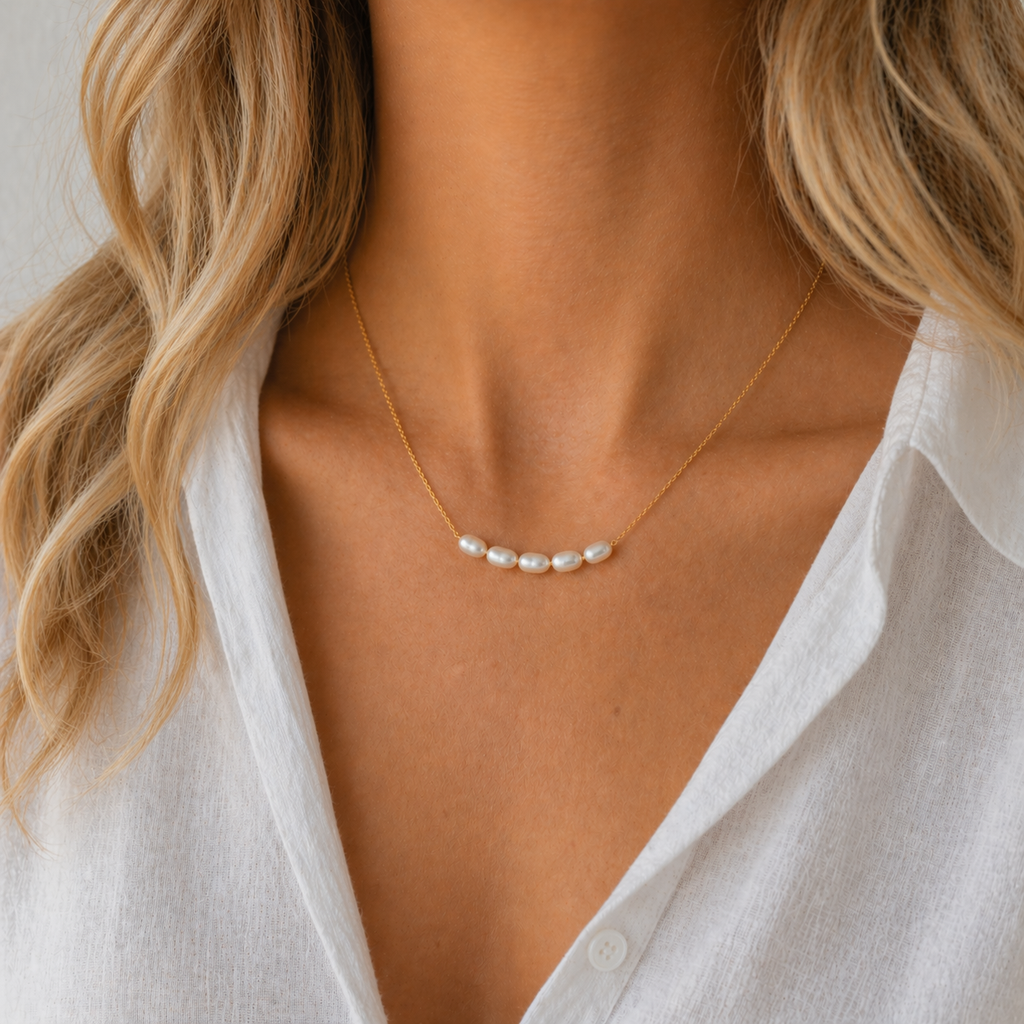 Lagoon pearl necklace with five organic pearls spaced along a fine stainless steel chain, available in gold and silver, worn at collarbone length.