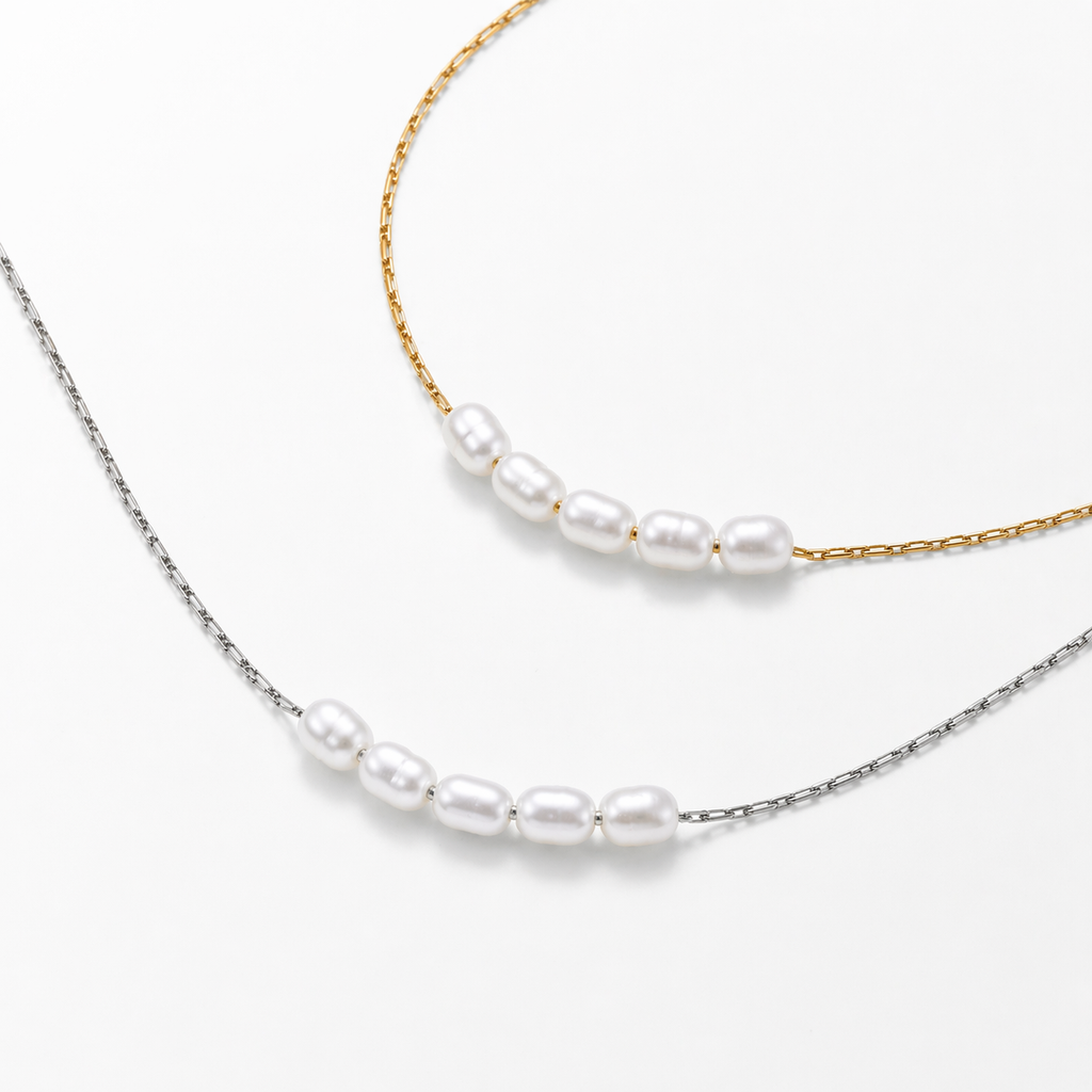 Lagoon pearl necklace with five organic pearls spaced along a fine stainless steel chain, available in gold and silver, worn at collarbone length.