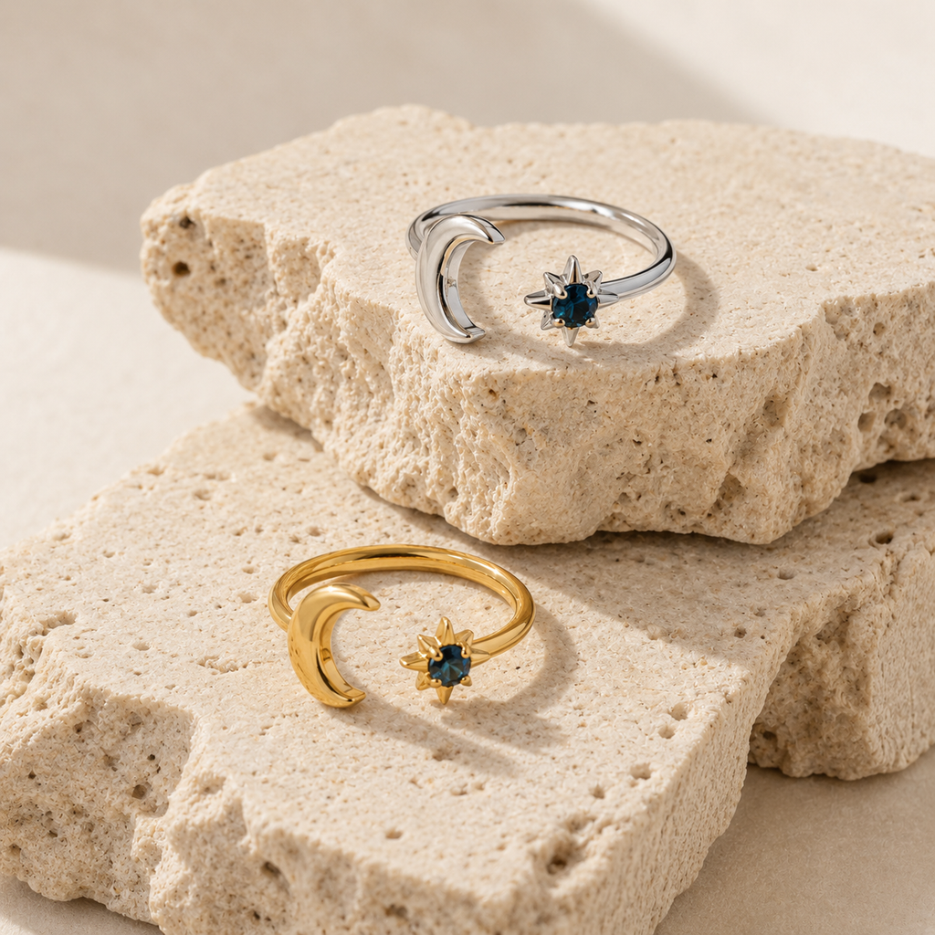 Gold and silver celestial moon and star adjustable ring with deep blue gemstone on white background.