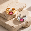 Gold and silver adjustable statement rings with oval pink crystal stones on a white background.