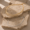Gold layered necklace featuring a flat snake chain and fine chain creating a minimal stacked jewellery look