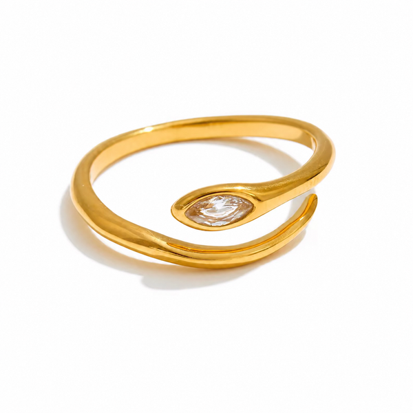 Gold and silver adjustable open-band rings with marquise crystal detail displayed on raw travertine stone.
