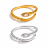 Gold and silver adjustable open-band rings with marquise crystal detail displayed on raw travertine stone.
