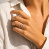 Gold and silver adjustable open-band rings with marquise crystal detail displayed on raw travertine stone.
