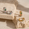 Gold and silver huggie earrings with colourful gemstone settings including green, pink, and blue stones with a star detail.