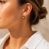 Gold huggie earrings with three stacked stones in green, clear and navy, textured bezel settings, minimal white background